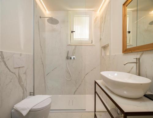 uma casa de banho branca com um lavatório e um chuveiro em Borgopetra Resort em Numana