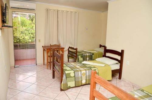 a room with three beds and a table and a window at Caminho da Costa Verde in Itaguaí