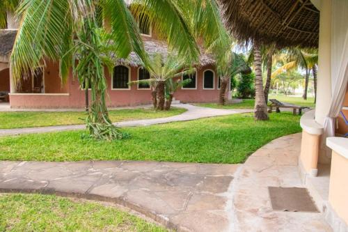 a walkway in front of a house with palm trees at Tembo Baharini Beach Cottage in Malindi