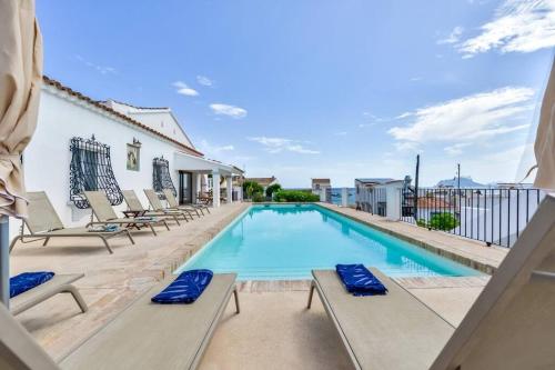 a swimming pool with lounge chairs next to a building at Villas Guzman - San Vicente in Moraira