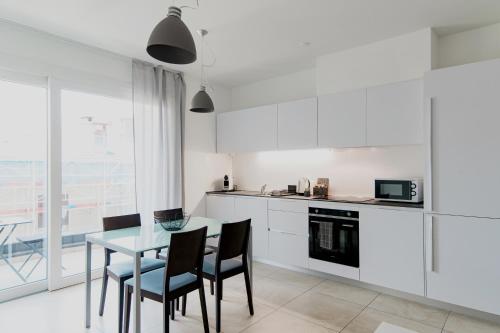 a kitchen with a table and chairs and a kitchen with white cabinets at Roggia Apartments by Quokka 360 - central flats with parking space in Lugano