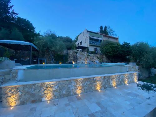 une piscine avec un mur en pierre et une maison dans l'établissement Dieu L'Amour - Molinard, à Châteauneuf