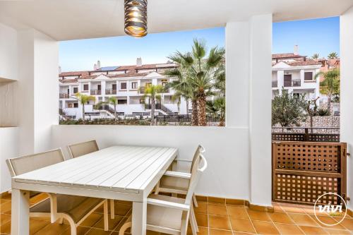 a white dining room with a table and chairs on a balcony at ViVi Homes - El Sembrador Pool, Terrace & Golf in La Cala de Mijas