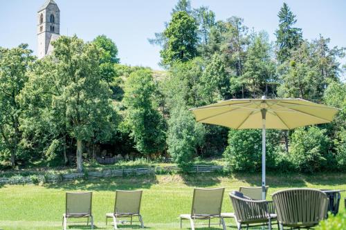 a group of chairs and an umbrella in the grass at hubertus dolomites in Fiè