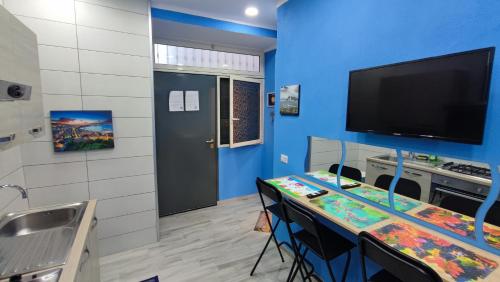 ナポリにあるGiulia's Houseの青い壁の客室で、テーブルとテレビが備わります。