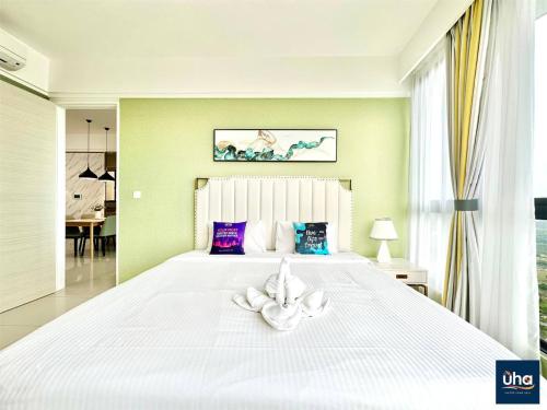 a bedroom with a large white bed with a white flower on it at Macrolink Medini by RR JBcity in Nusajaya