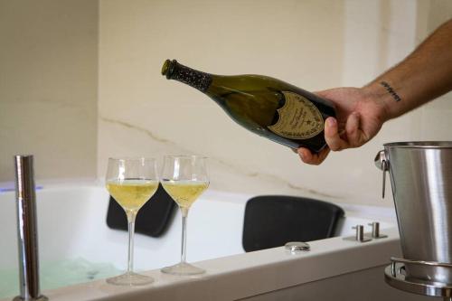 a person pouring a bottle of wine into two glasses at Luxury - 5 Stars - Suite with a jacuzzi 70's rooms in Trapani