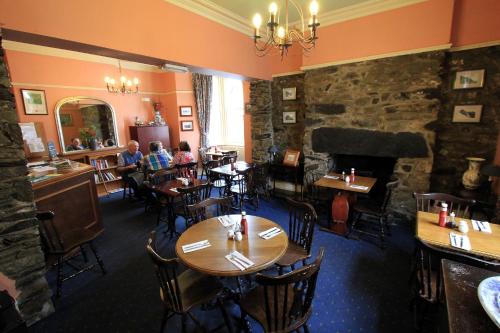a restaurant with tables and chairs and a stone wall at The Eagles Bunkhouse in Betws-y-coed