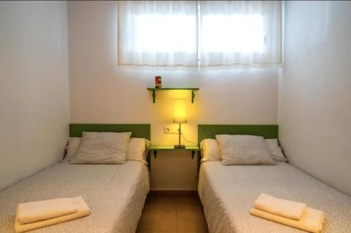 two twin beds in a room with a window at 2-Bed Penthouse Apartment in Roldán