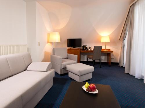 a living room with a white couch and a table at ACHAT Hotel Neustadt an der Weinstraße in Neustadt an der Weinstraße