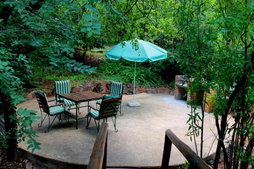 een patio met een tafel en stoelen en een parasol bij On Golden Pond - Mount Amanzi in Hartbeespoort