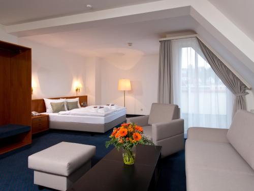 a hotel room with a bed and a couch at ACHAT Hotel Neustadt an der Weinstraße in Neustadt an der Weinstraße