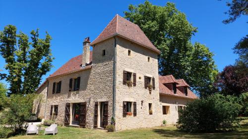 an old stone building with a turret on a field at Ferme des Petites Oreilles 4 étoiles in Montignac
