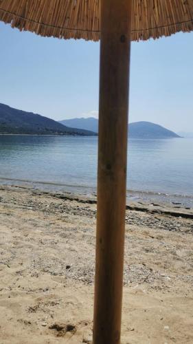a straw umbrella on a beach with the water at Maurizio's Villa in Yiáltra