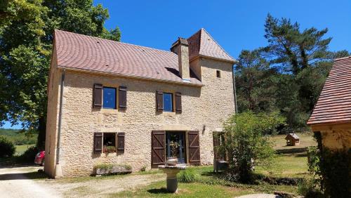 an old brick house with blue windows and a roof at Ferme des Petites Oreilles 4 étoiles in Montignac