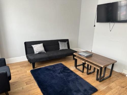 uma sala de estar com um sofá preto e uma mesa em Eva Suites em Gillingham