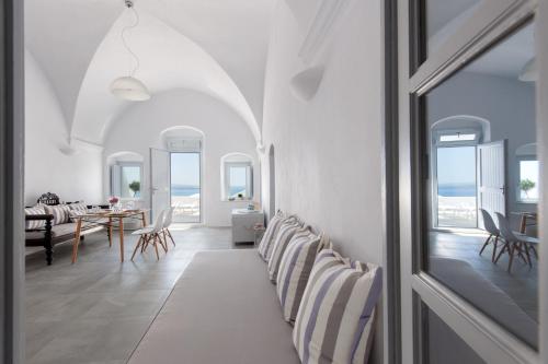 Habitación blanca con comedor y mesa en Evmenia Luxury Cave Villa, en Oia
