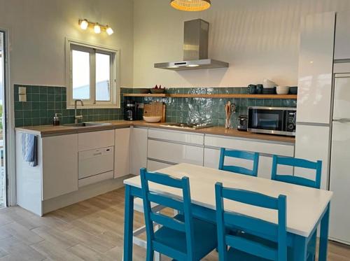 a kitchen with a table and blue chairs in it at Hestia's House in Meganisi