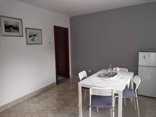 uma cozinha com uma mesa e cadeiras brancas e um frigorífico em Kosmajska Vila em Koraćica