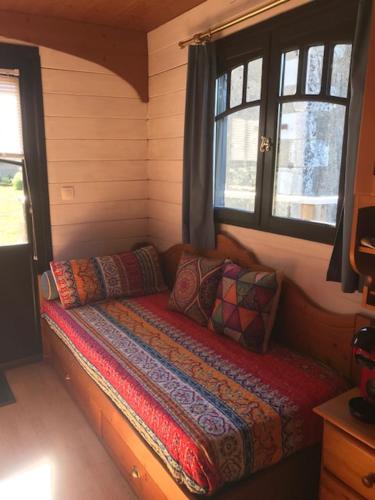 Cama pequeña en habitación con 2 ventanas en Lou Bohème, en Le Briou