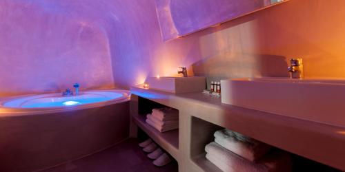 une salle de bain avec deux lavabos et une baignoire dans l'établissement Evmenia Luxury Cave Villa, à Oia