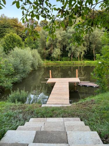 un puente de madera sobre un estanque en un parque en Drewniana chata nad stawem, en Krasiczyn