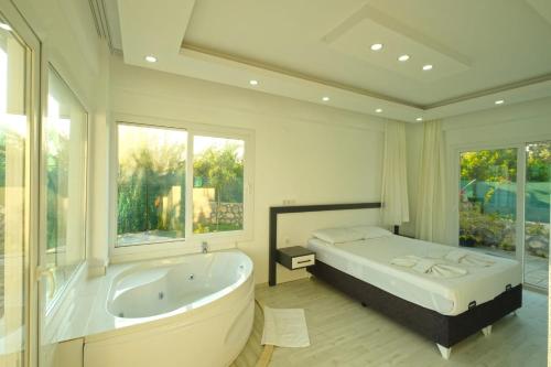 een grote badkamer met een groot bad en een bed bij Villa tiele in Fethiye