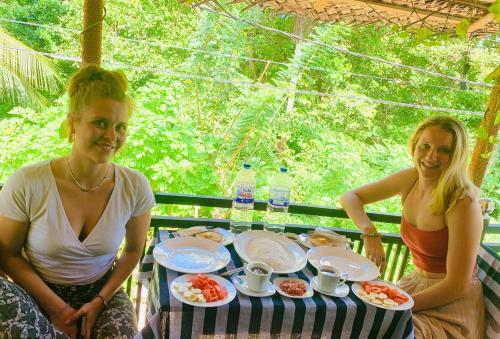 two women sitting at a table with food on it at Vinu’s Place in Matara