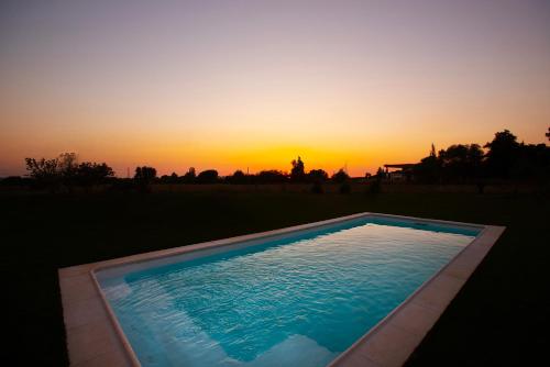 a swimming pool with a sunset in the background at Estremoz Hotel in Estremoz