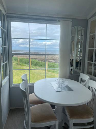 a white table and chairs in a room with a window at Amazing holiday home with sea views in Newcastle upon Tyne