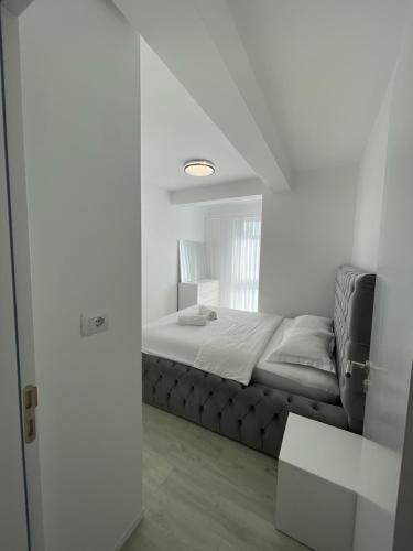 a white bedroom with a bed and a window at Gega Apartments in Gjakove