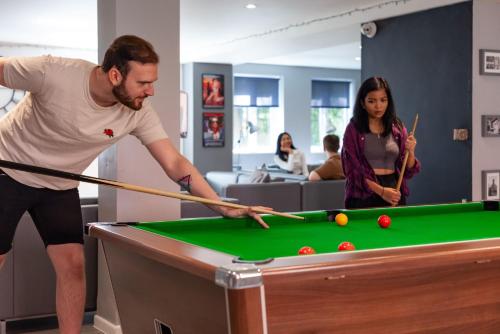a man and a woman playing pool with a cue at For Students Only - Park Court in Lincoln in Lincoln