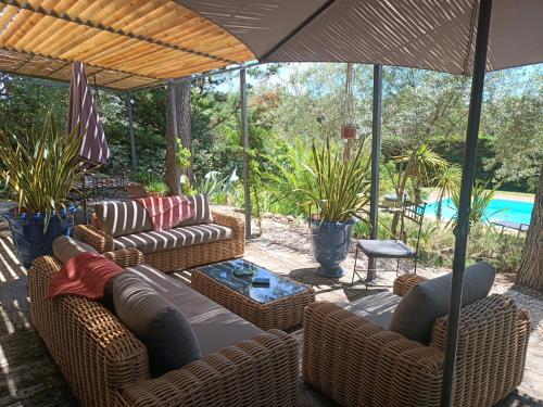 une terrasse avec des canapés, une table et un parasol dans l'établissement Villa provençale et ses grands pins, à Pernes-les-Fontaines