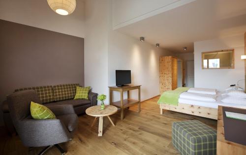 a hotel room with a bed and a couch and a chair at Naturhotel Bauernhofer in Heilbrunn