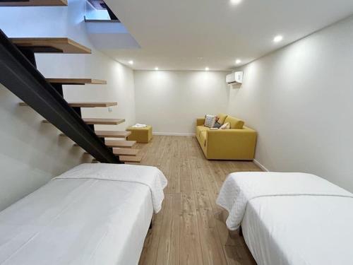 a room with two beds and a yellow couch at Casinha da Arcela in Guimarães