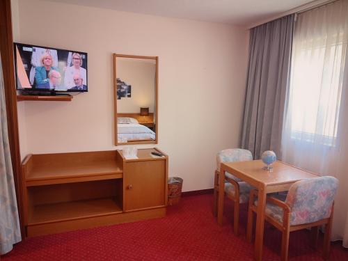 a room with a bed and a table and a mirror at Hôtel des Trois Rois in Le Locle