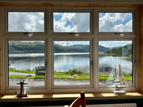 a window with a view of a lake and a sail boat at The Strontian Hotel in Strontian