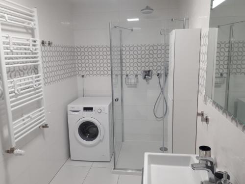 y baño blanco con lavadora y ducha. en Apartamenty BEST HOME & SPA, en Ustronie Morskie