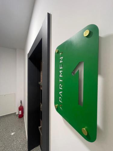 a green sign with the number one on a wall at Gega Apartments in Gjakove