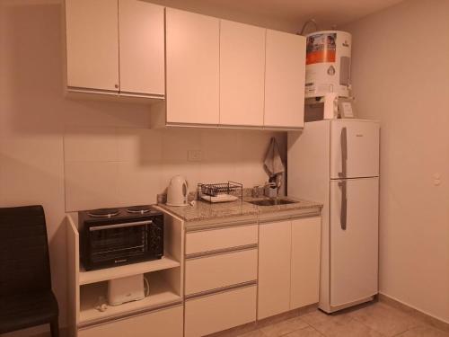 cocina con armarios blancos y nevera blanca en Kalay Home Resistencia-Alquiler Monoambiente temporario en Resistencia