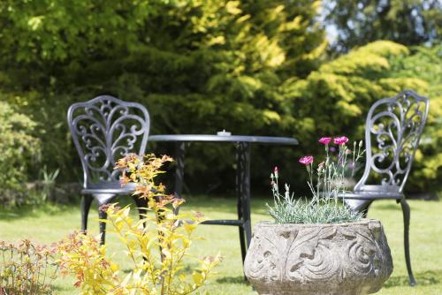 two chairs and a table in a yard with flowers at Woodlands Lodge Hotel in Bartley