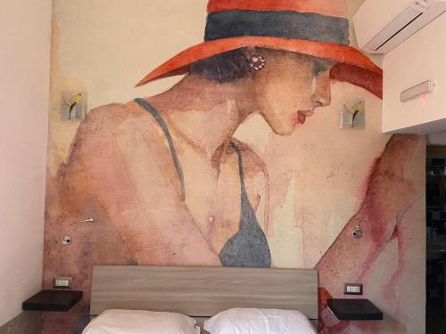 una pintura de una mujer con un sombrero en la pared en Maison Belle Époque & suites, en Oristano