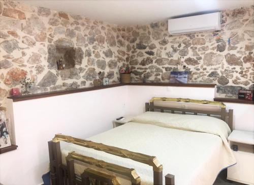 a bedroom with a bed and a stone wall at METAXIAS HOUSE in Leonidio