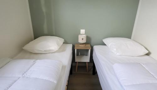 - 2 lits jumeaux dans une chambre avec une petite table dans l'établissement Résidence Belle Plage 2, à Asnelles