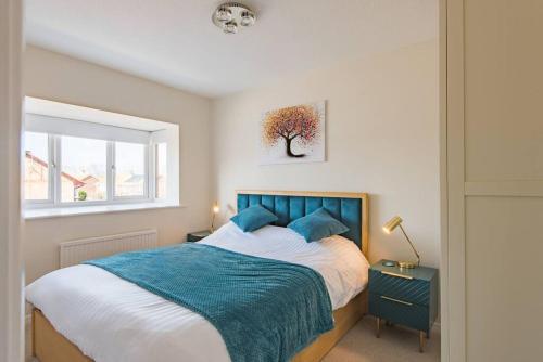 a bedroom with a bed with a blue blanket and a window at Links Bay - 100 yards from beach and golf course in Deal