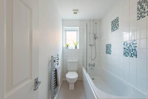 a white bathroom with a toilet and a bath tub at Links Bay - 100 yards from beach and golf course in Deal
