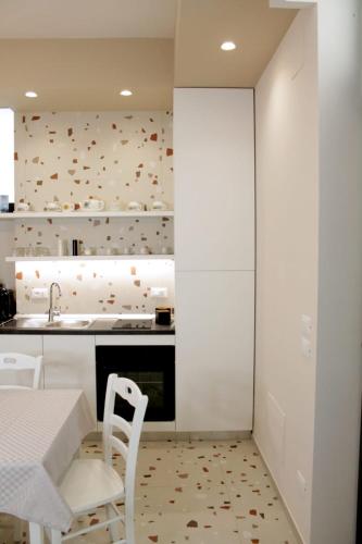 a kitchen with white cabinets and a table and chairs at Casa Vacanze Mariantò in Noci