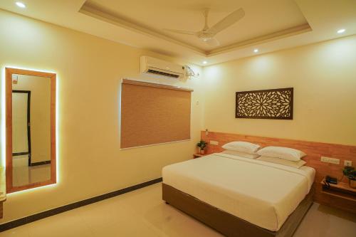 a bedroom with a bed and a window and a mirror at TPC Camphor in Tiruchchirāppalli