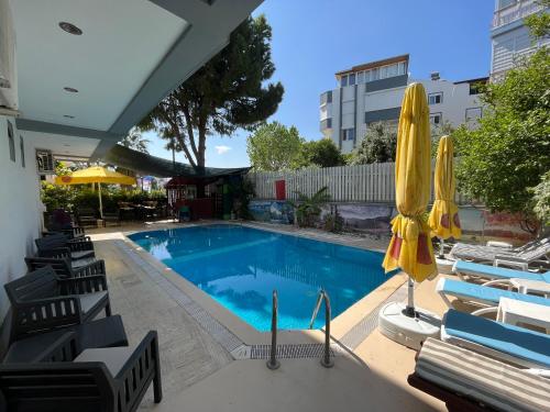 a swimming pool with chairs and a yellow umbrella at Hotel Lunay in Antalya