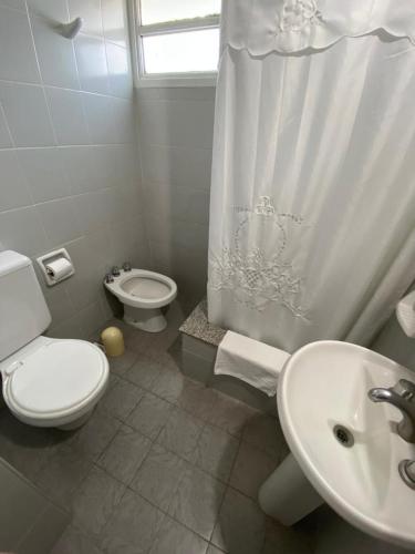 a white bathroom with a toilet and a sink at Hotel Plaza in Coronel Suárez